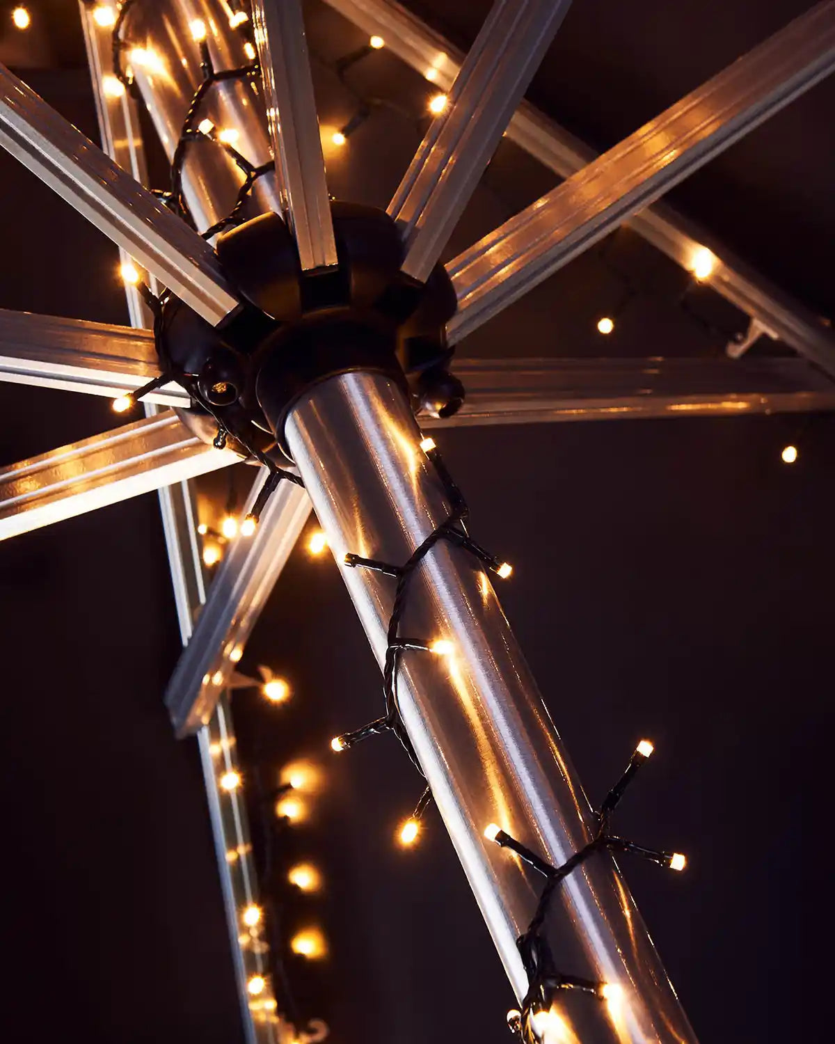 Outdoor umbrella with warm white string lights against a dark background