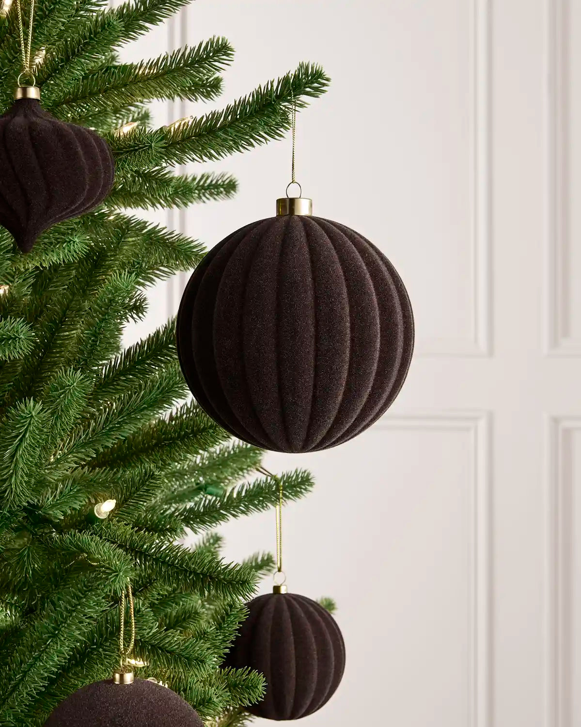 Oversized 15 cm Espresso velvet Ribbed bauble styled among matching decorations on a Christmas tree.
