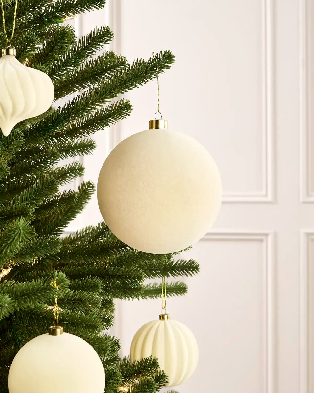 Oversized 15 cm latte velvet traditional bauble styled among matching decorations on a Christmas tree.
