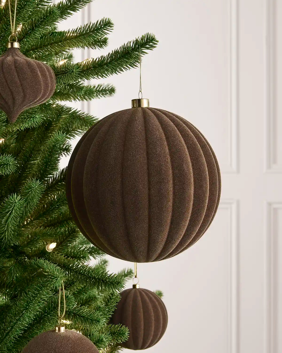 Oversized 20 cm Mocha velvet Ribbed bauble styled among matching decorations on a Christmas tree.
