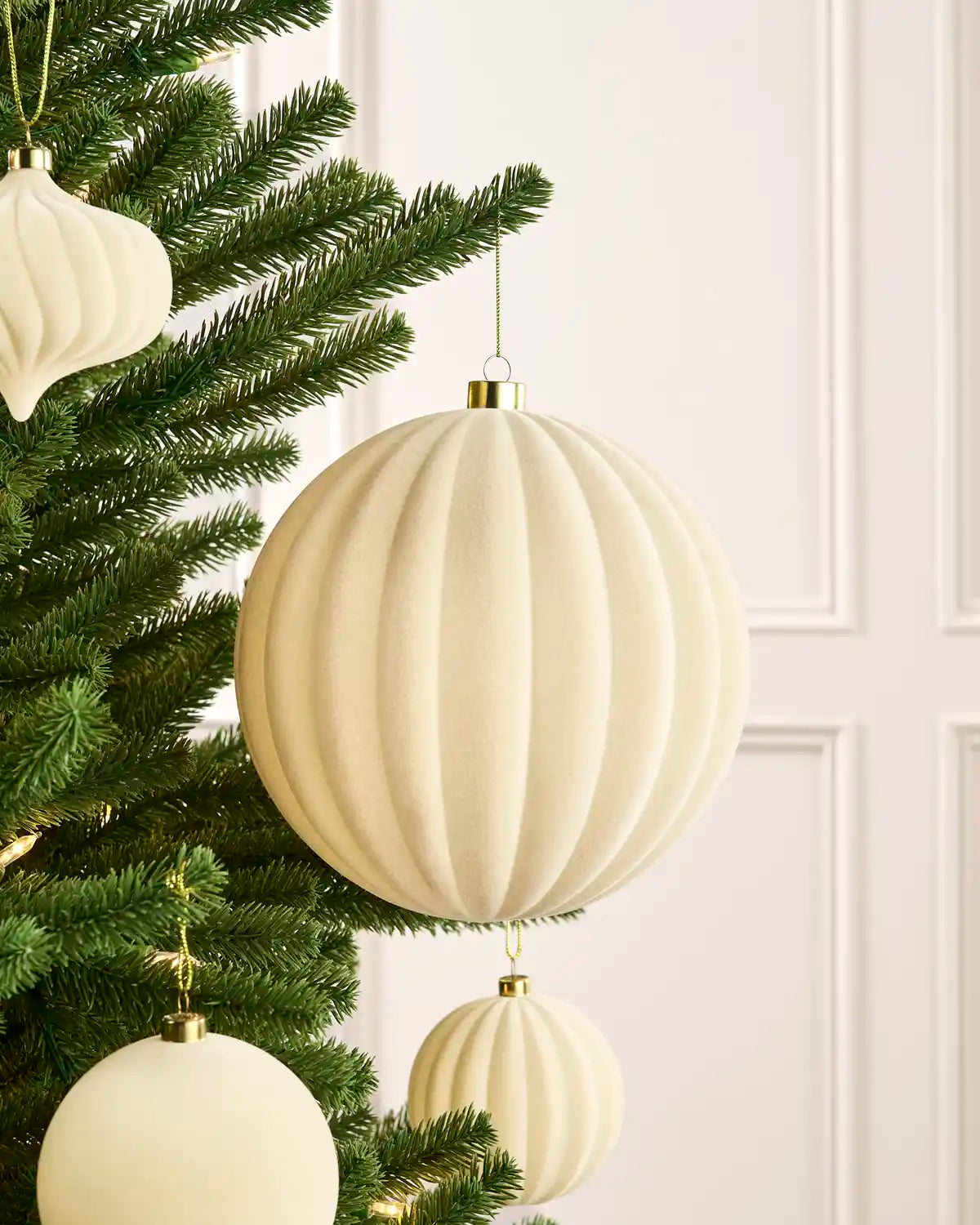 Oversized 20 cm latte velvet Ribbed bauble styled among matching decorations on a Christmas tree.
