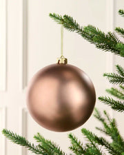 Oversized Bauble hanging from a Christmas tree against a cream background