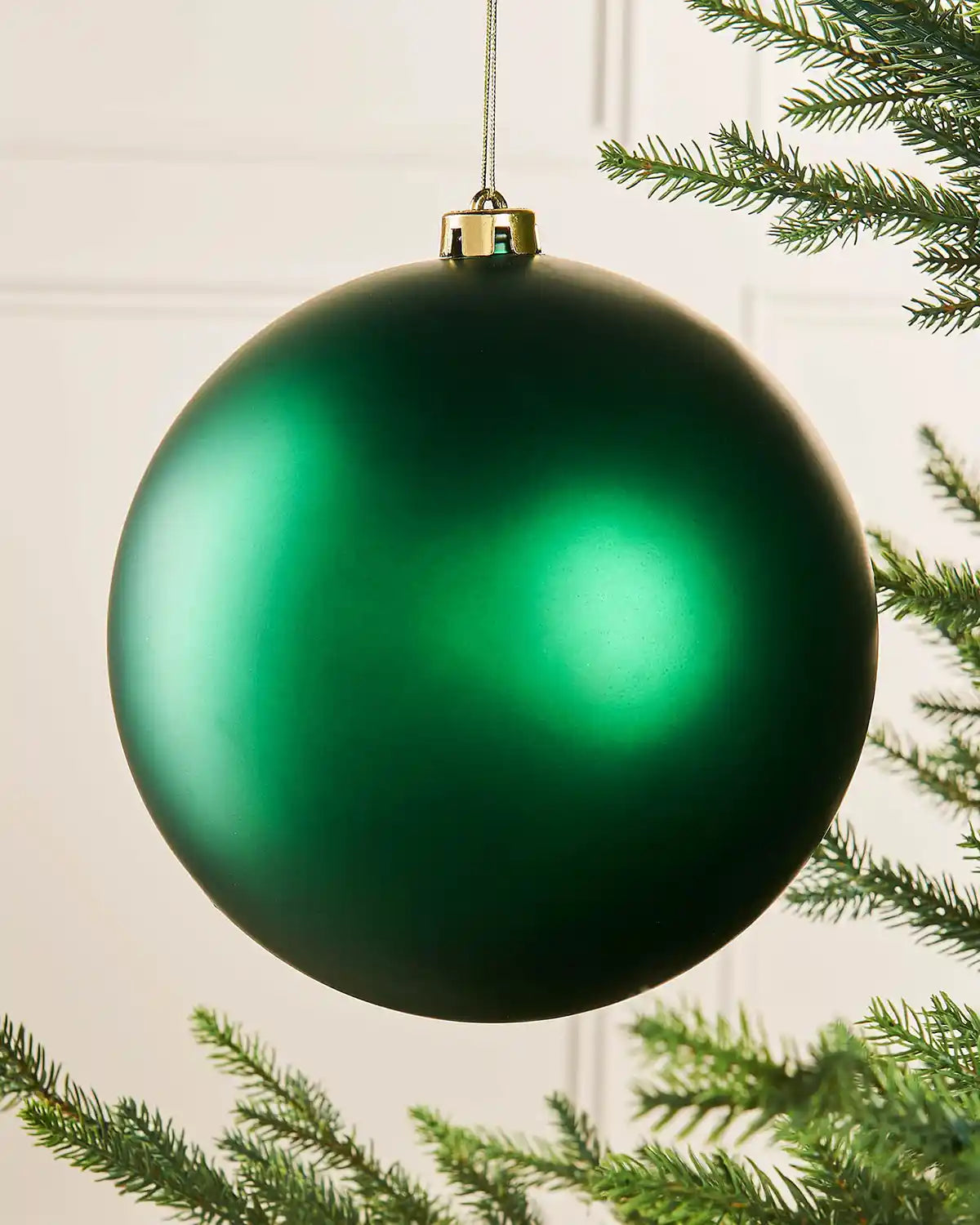 Oversized Christmas green matt bauble on a Christmas tree branch