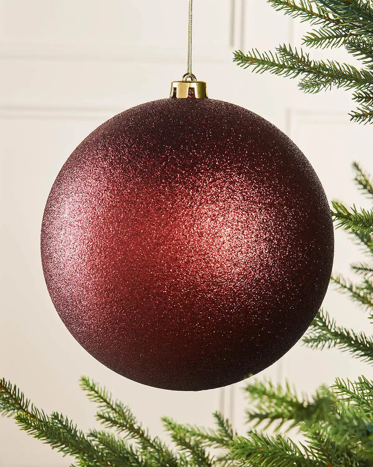 Oversized glitter Burgundy bauble on a Christmas tree branch