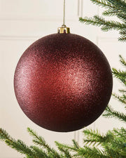 Oversized glitter Burgundy bauble on a Christmas tree branch