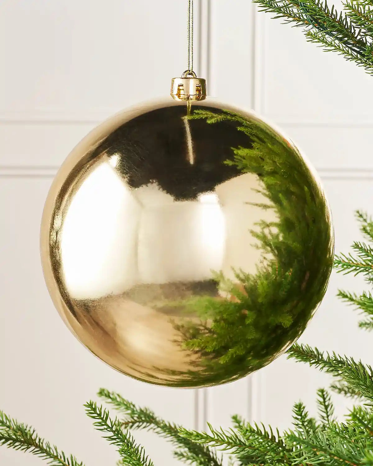 Oversized gloss gold bauble on a Christmas tree branch