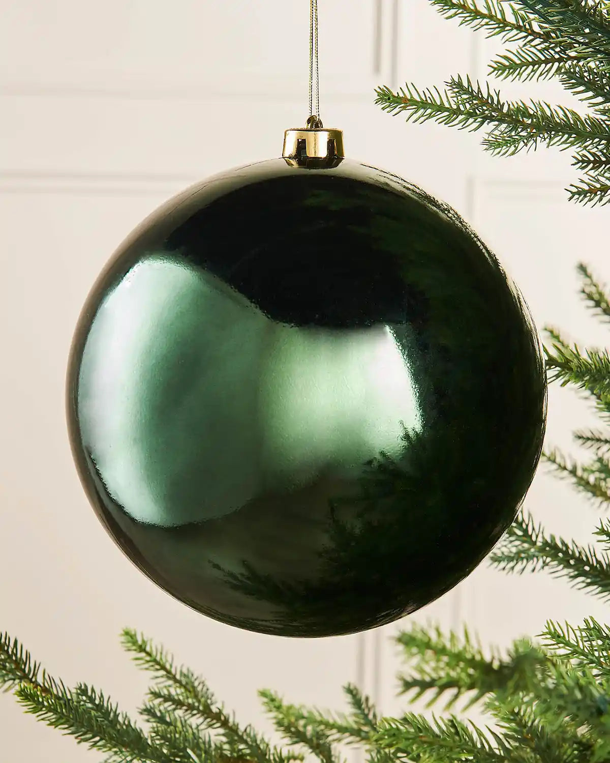 Oversized gloss green bauble on a Christmas tree branch