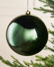 Oversized gloss green bauble on a Christmas tree branch