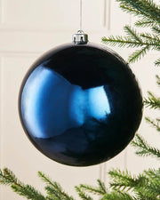 Oversized navy blue gloss bauble on a Christmas tree branch
