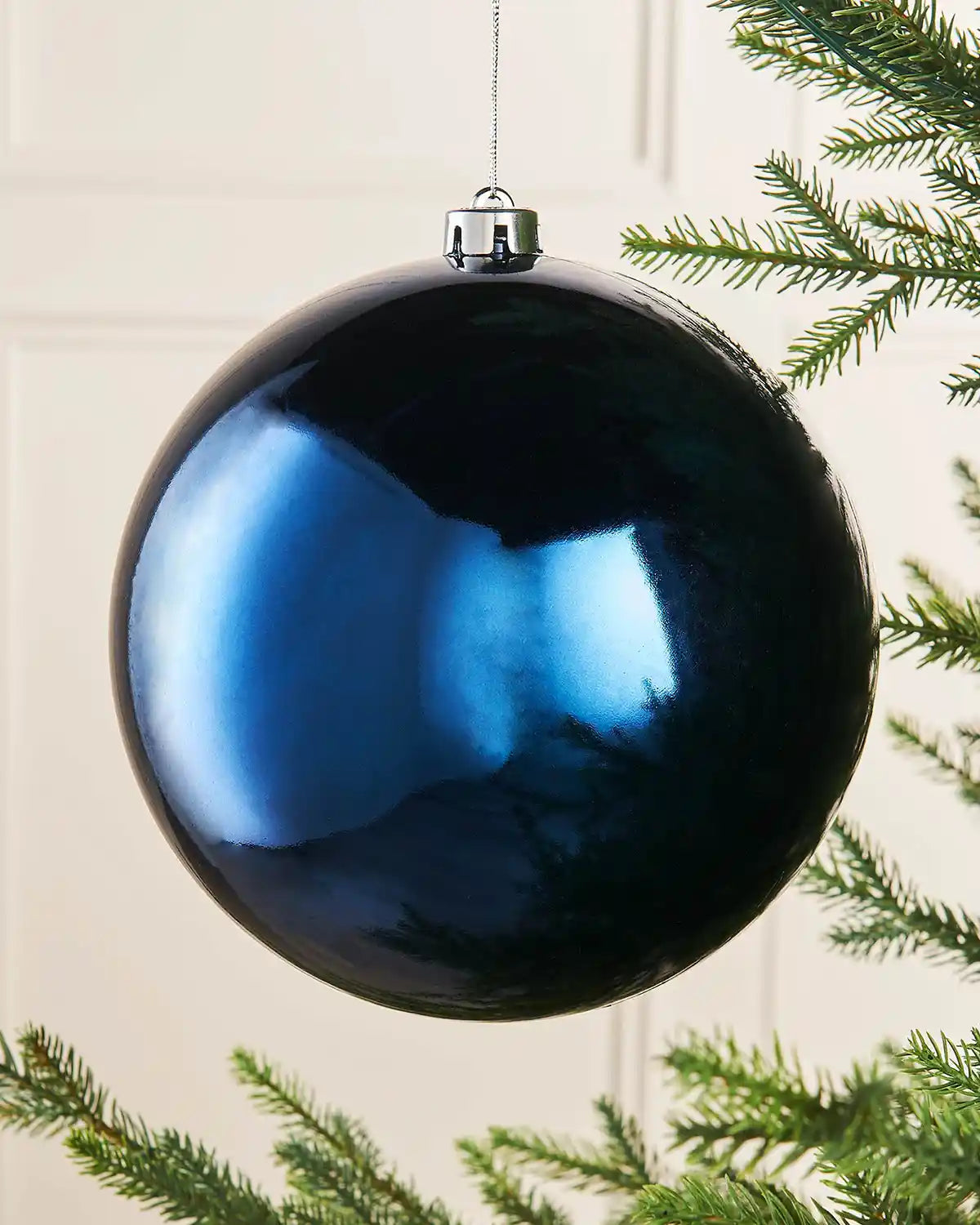 Oversized navy blue gloss bauble on a Christmas tree branch
