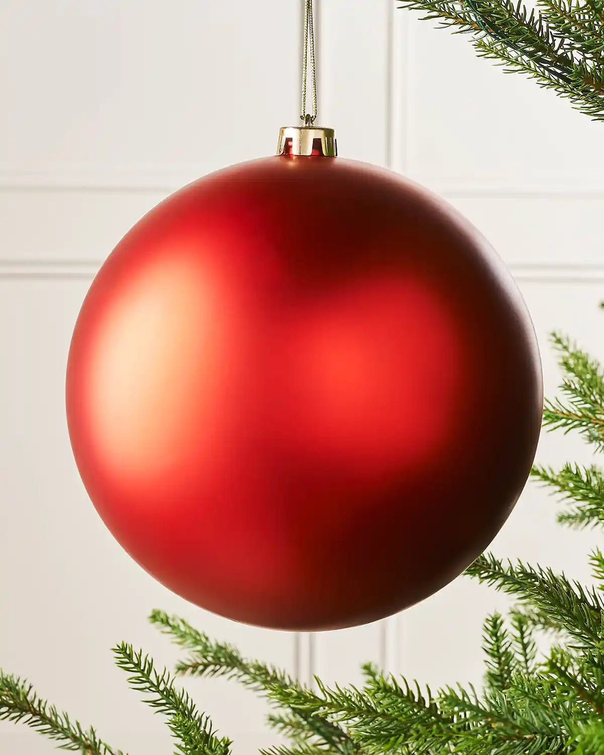 Oversized red matt bauble on a Christmas tree branch