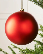 Oversized red matt bauble on a Christmas tree branch