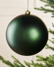 Oversized sage green bauble on a Christmas tree branch