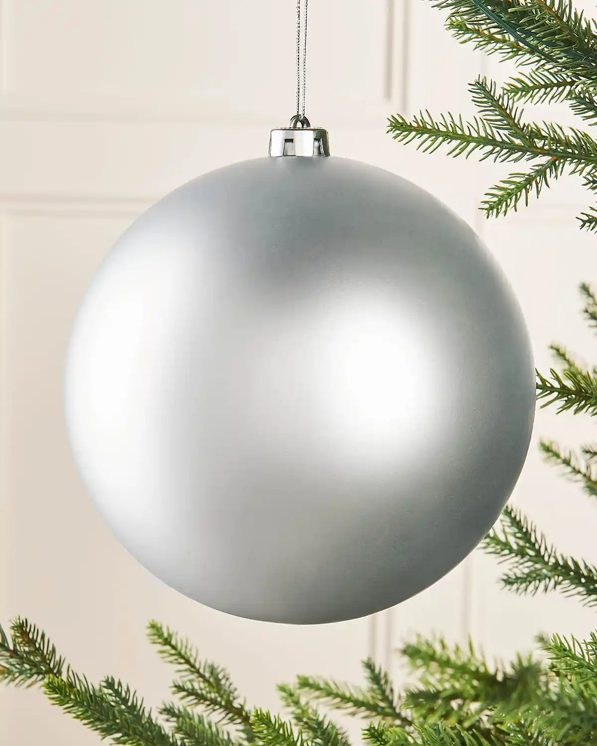 Oversized silver bauble on a Christmas tree branch
