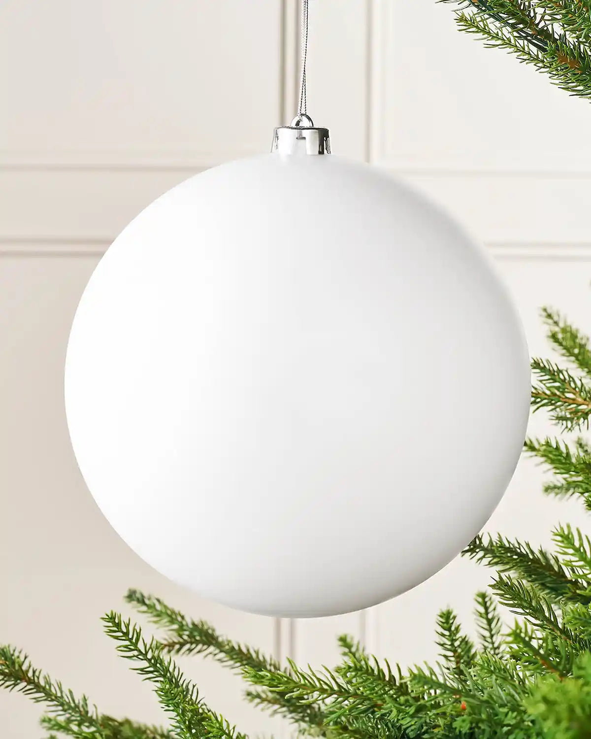 Oversized white matt bauble on a Christmas tree branch