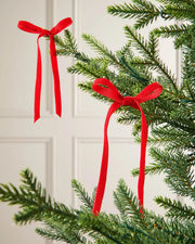 A pair of red velvet bows on the end of Christmas tree branches