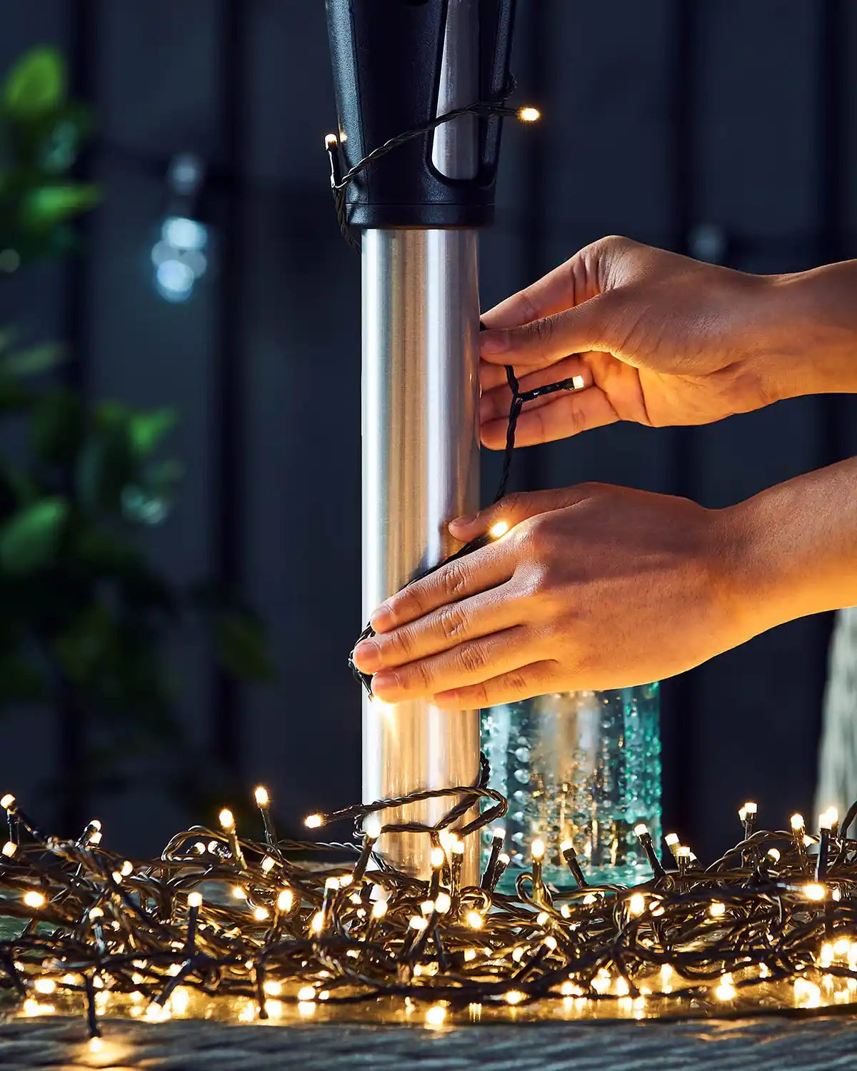 Person adjusting  warm white string lights on a dark background