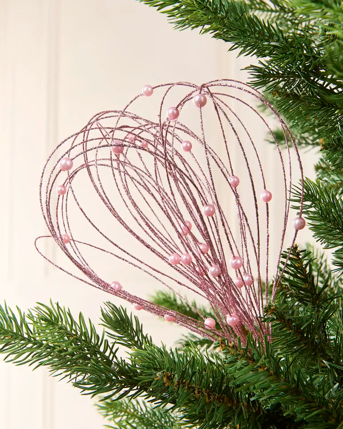 Pink Glitter Nest Christmas Tree Pick placed in green Christmas tree branches with a cream background
