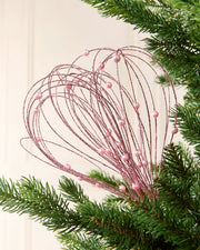 Pink Glitter Nest Christmas Tree Pick placed in green Christmas tree branches with a cream background
