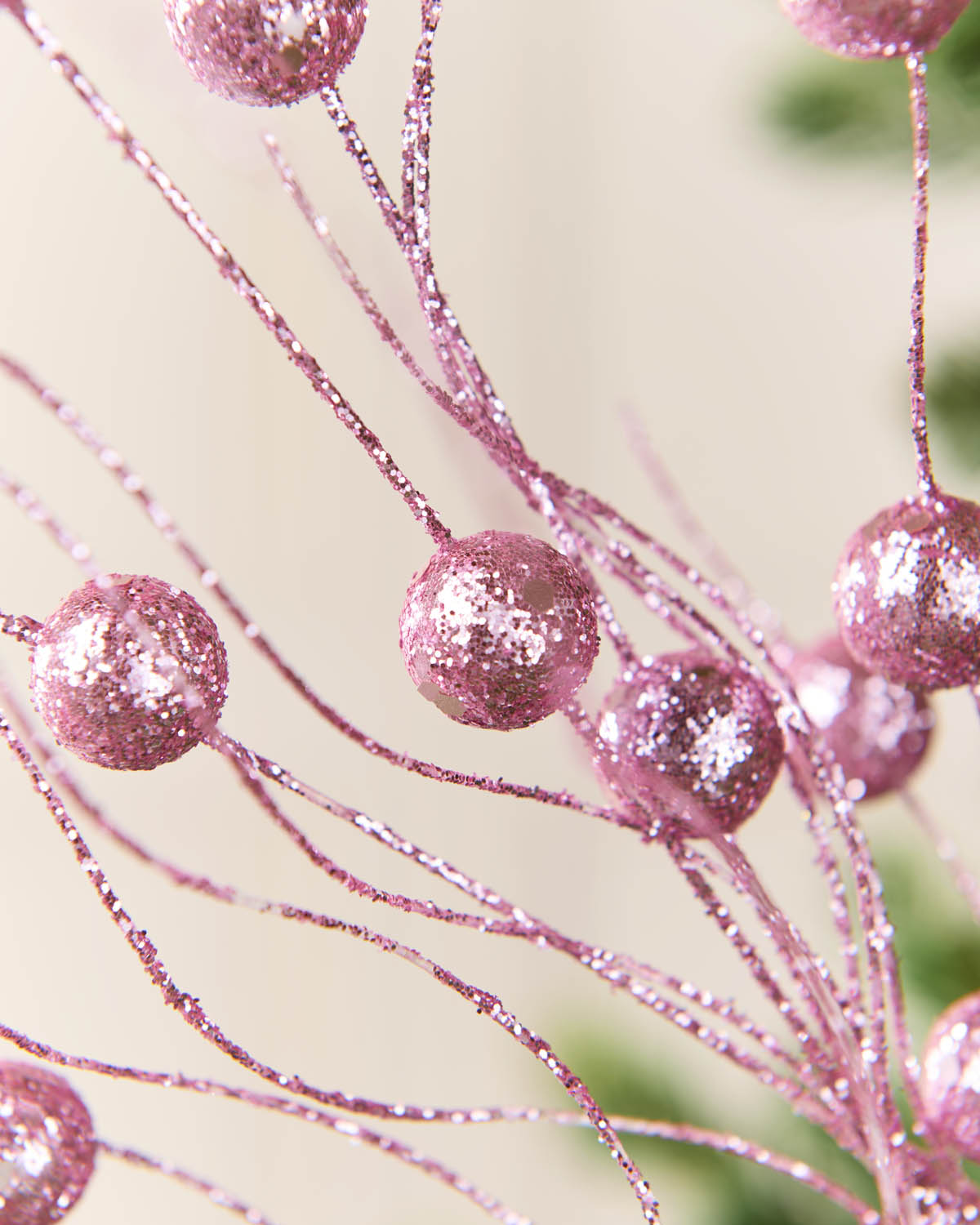 Pink glittery decorative branches with round glittering beads on a soft beige background.