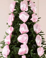 Pink satin ribbon draped and arranged on a green Christmas tree.