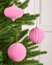 Pink velvet baubles classic round and onion shapes with smooth and swirl patterns, hanging from Christmas tree branches