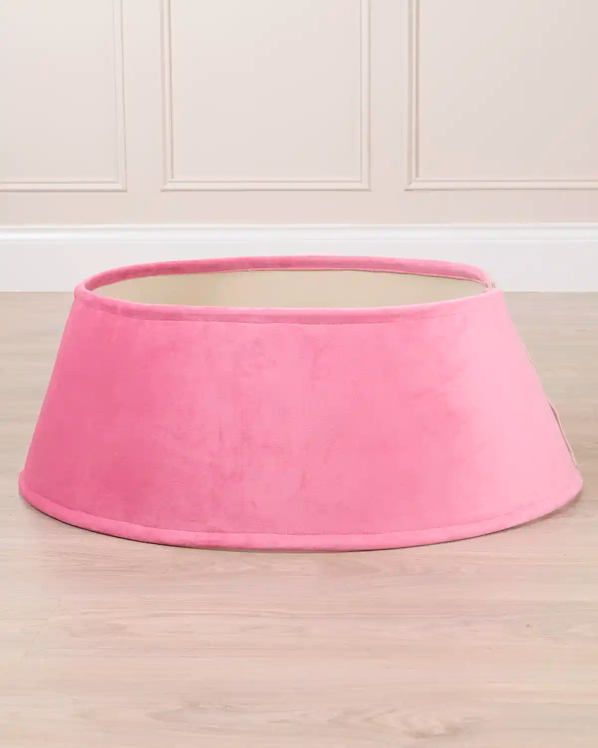Pink velvet tree skirt displayed by itself, showing its circular shape, flared silhouette, and open center.