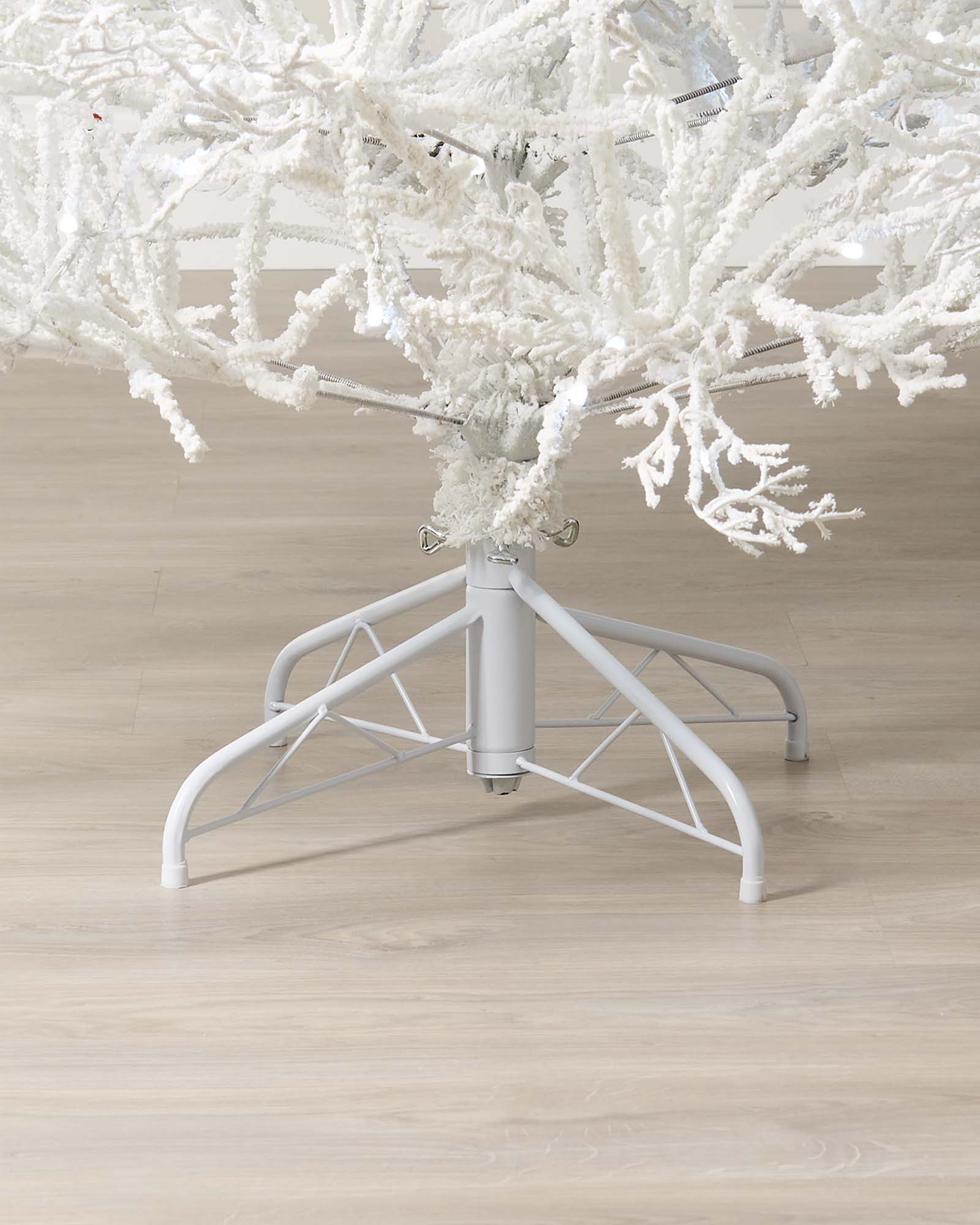 Minimalistic pre-lit white Arctic Ice Twig Christmas tree with snow-flocked PE/PVC branches, glowing with bright white LED lights against a neutral wall—crafted for easy setup and timeless winter charm.