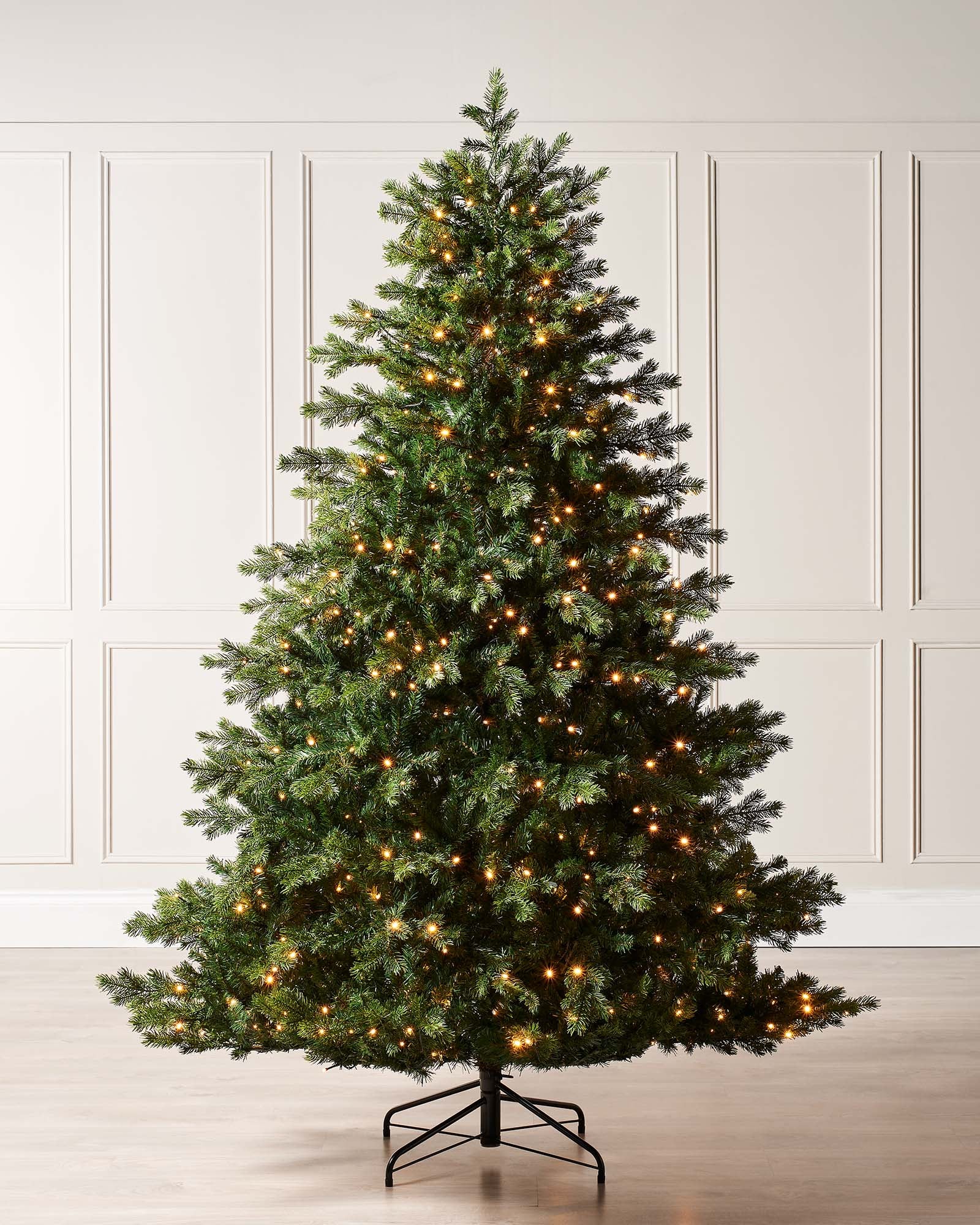 Pre-lit Balsam Fir Christmas tree with lush PE and PVC tips, adorned with warm white LED lights, displayed against a white wall—realistic, full-bodied, and perfect for creating a warm, elegant festive ambiance indoors or out.