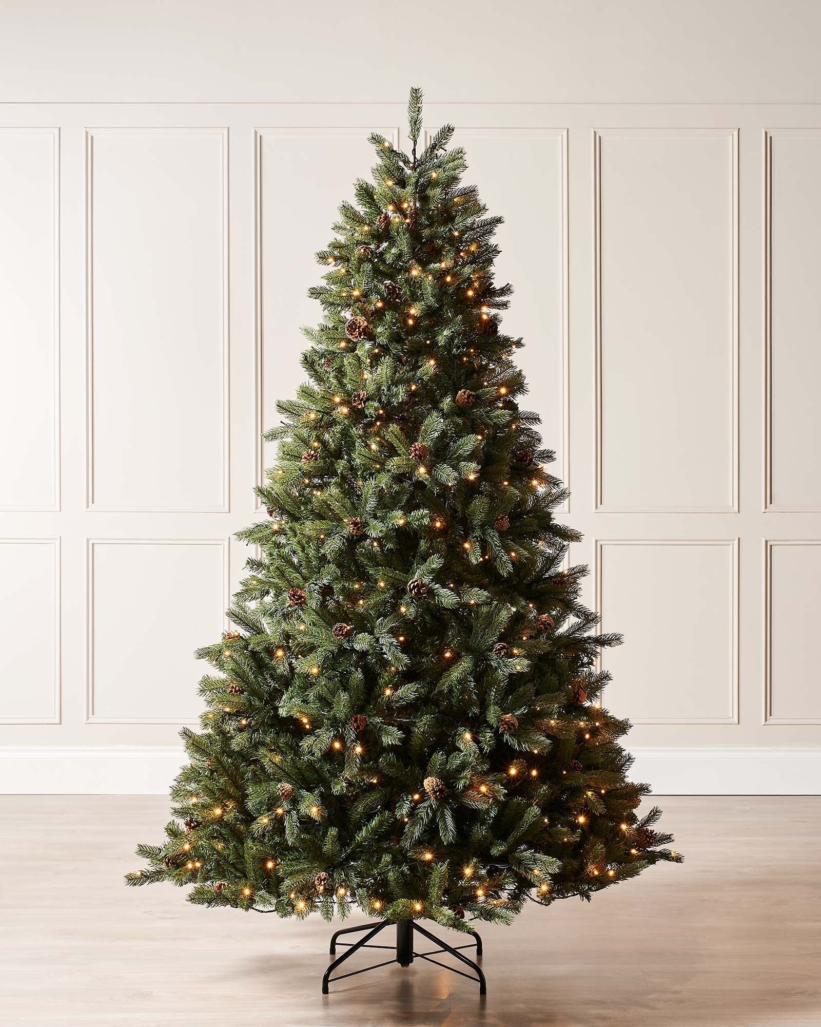 Pre-lit Craford Pine Christmas tree with dense PE/PVC branches, warm white LED lights, and realistic pinecones—lush, lifelike, and displayed against a neutral background for a cosy, traditional festive look.