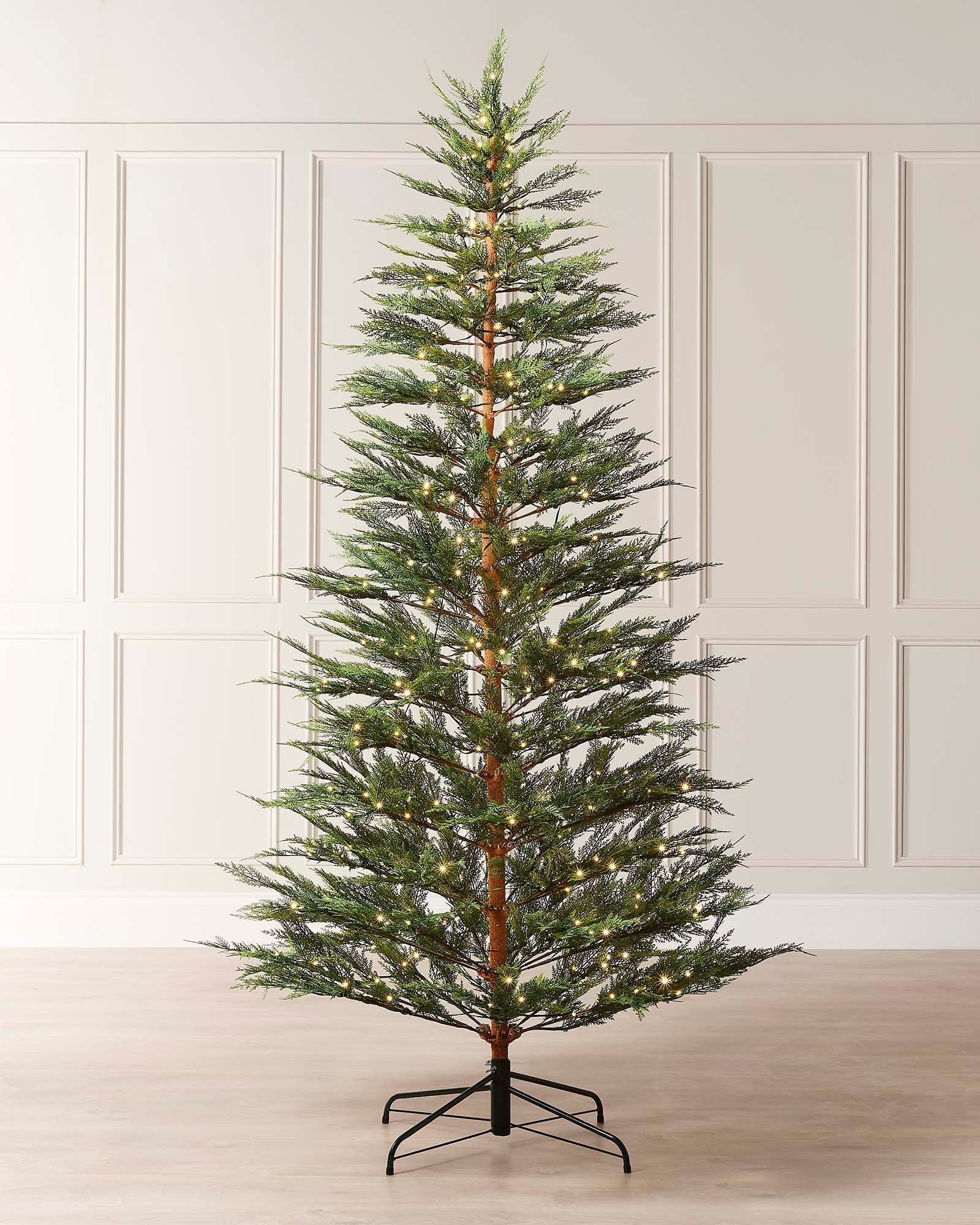 A pre-lit Cypress Fir Christmas tree with green branches and white lights, displayed against a neutral background.