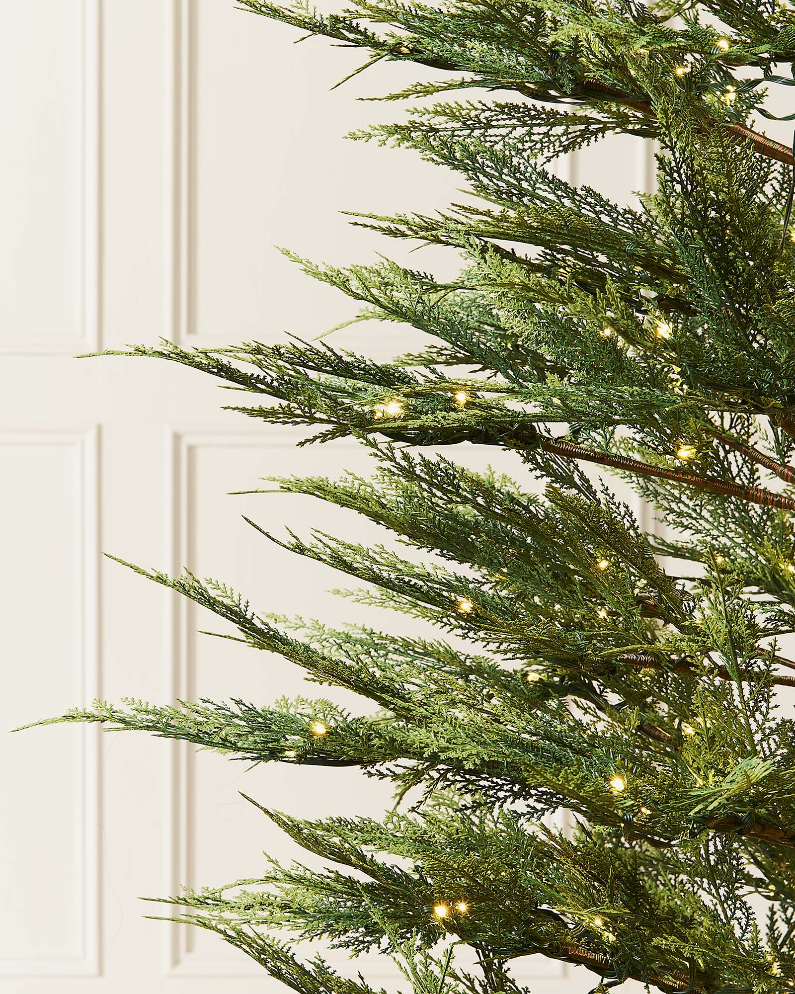 A pre-lit Cypress Fir Christmas tree with green branches and white lights, displayed against a neutral background.