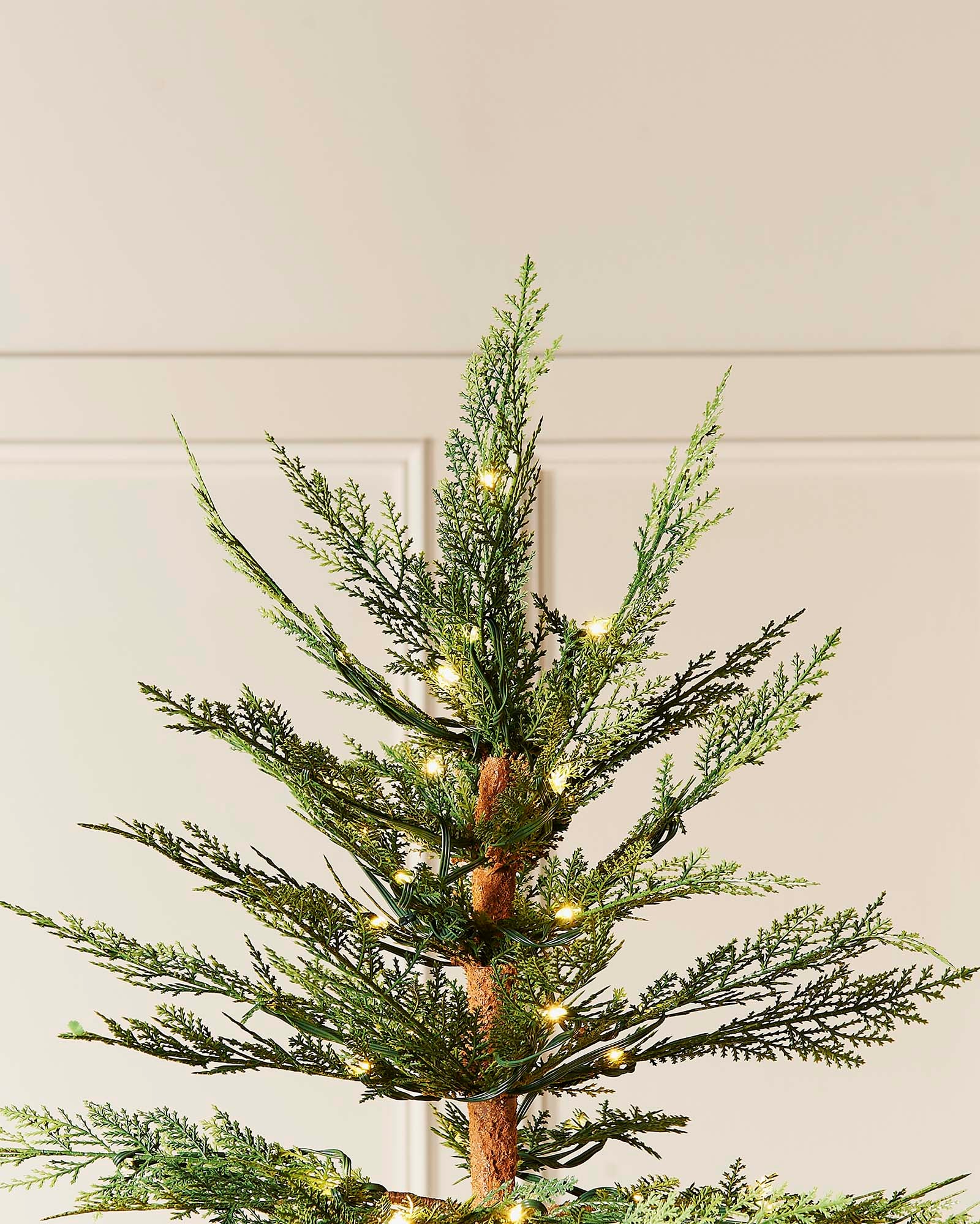 A pre-lit Cypress Fir Christmas tree with green branches and white lights, displayed against a neutral background.