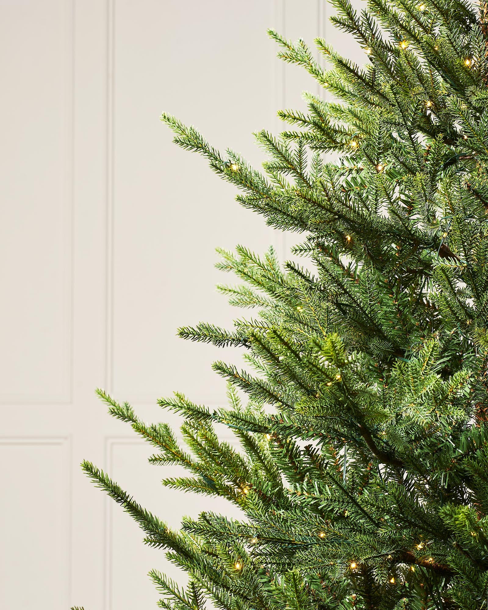 Pre-lit artificial Douglas Fir Christmas tree with warm white copper wire LED lights, available in green or snow-flocked finish, featuring lifelike PE and PVC branches and 8 lighting functions, displayed against a plain background.