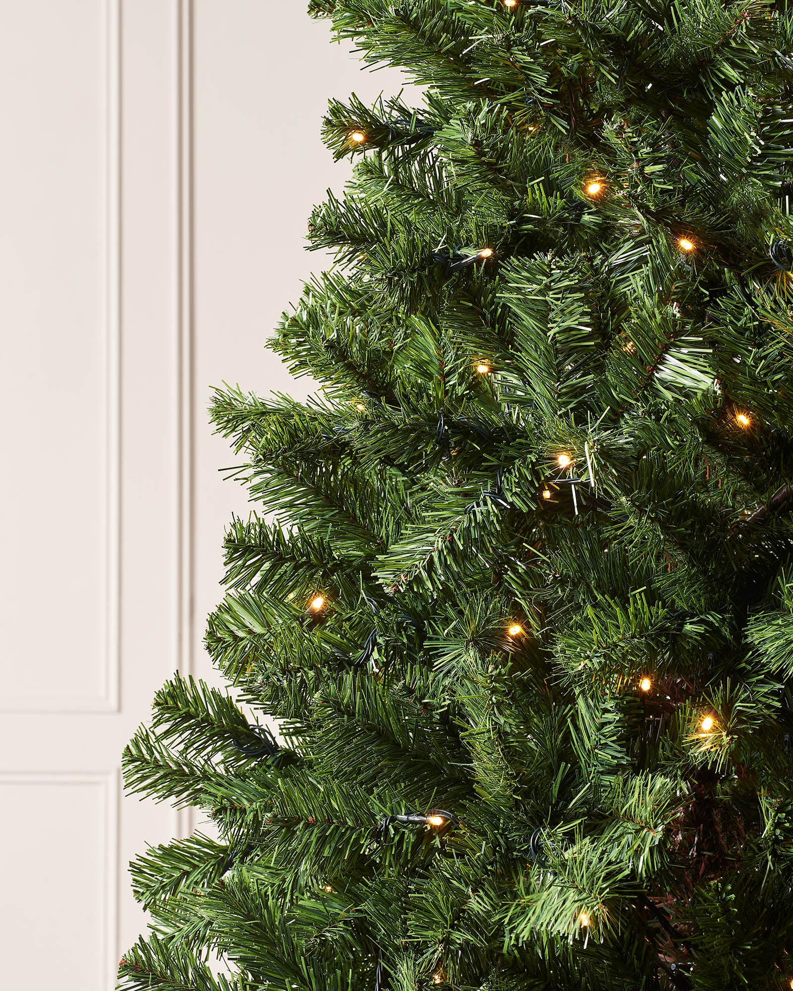 "6-foot pre-lit Emerald Spruce artificial Christmas tree with 556 PVC tips and 200 warm white LED lights, featuring 8 lighting functions, displayed indoors against a plain wall.