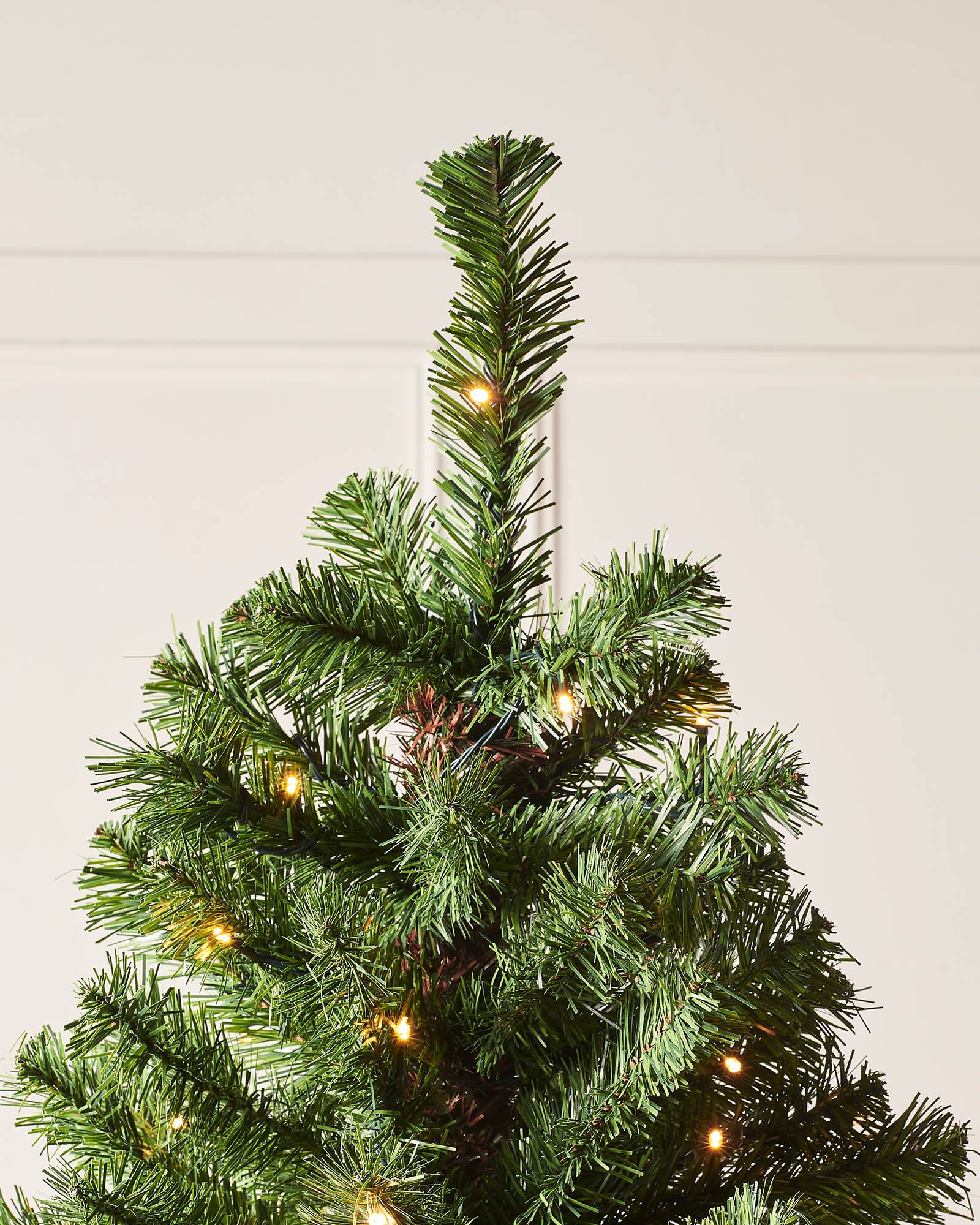 "6-foot pre-lit Emerald Spruce artificial Christmas tree with 556 PVC tips and 200 warm white LED lights, featuring 8 lighting functions, displayed indoors against a plain wall.