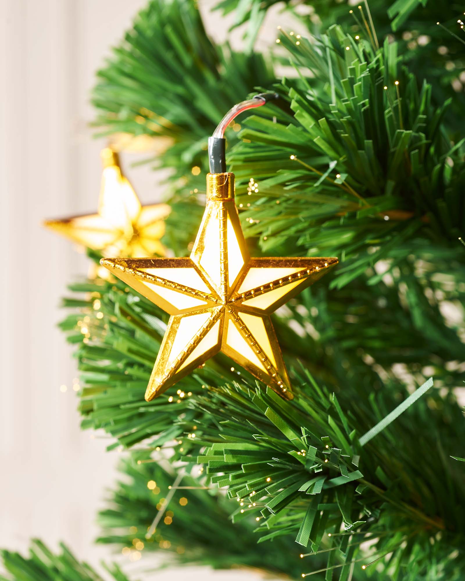7-foot pre-lit green artificial Christmas tree with 270 warm white fibre optic tips and 60 gold LED star decorations, featuring 8 lighting functions and an LED star topper, displayed indoors against a white background.