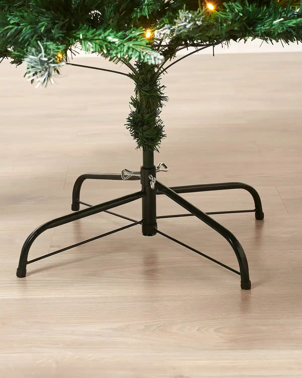 Pre-Lit Frosted Mixed Pine Christmas Tree, 7ft with black stand on a wooden floor.