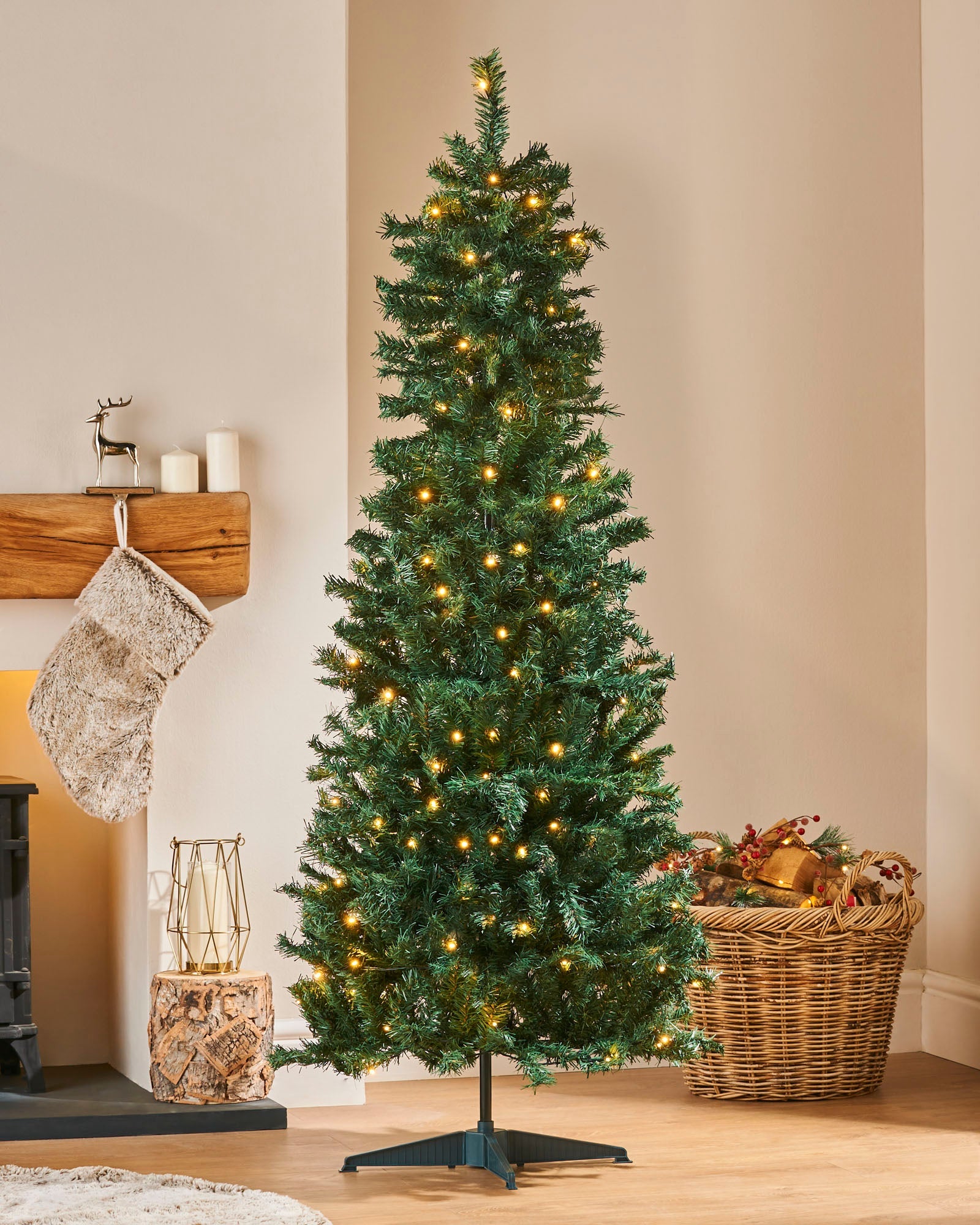 5 ft pre-lit Highland Pop-Up Christmas tree with warm white LED lights, featuring lush green PVC branches, placed beside a decorated fireplace with festive ornaments.