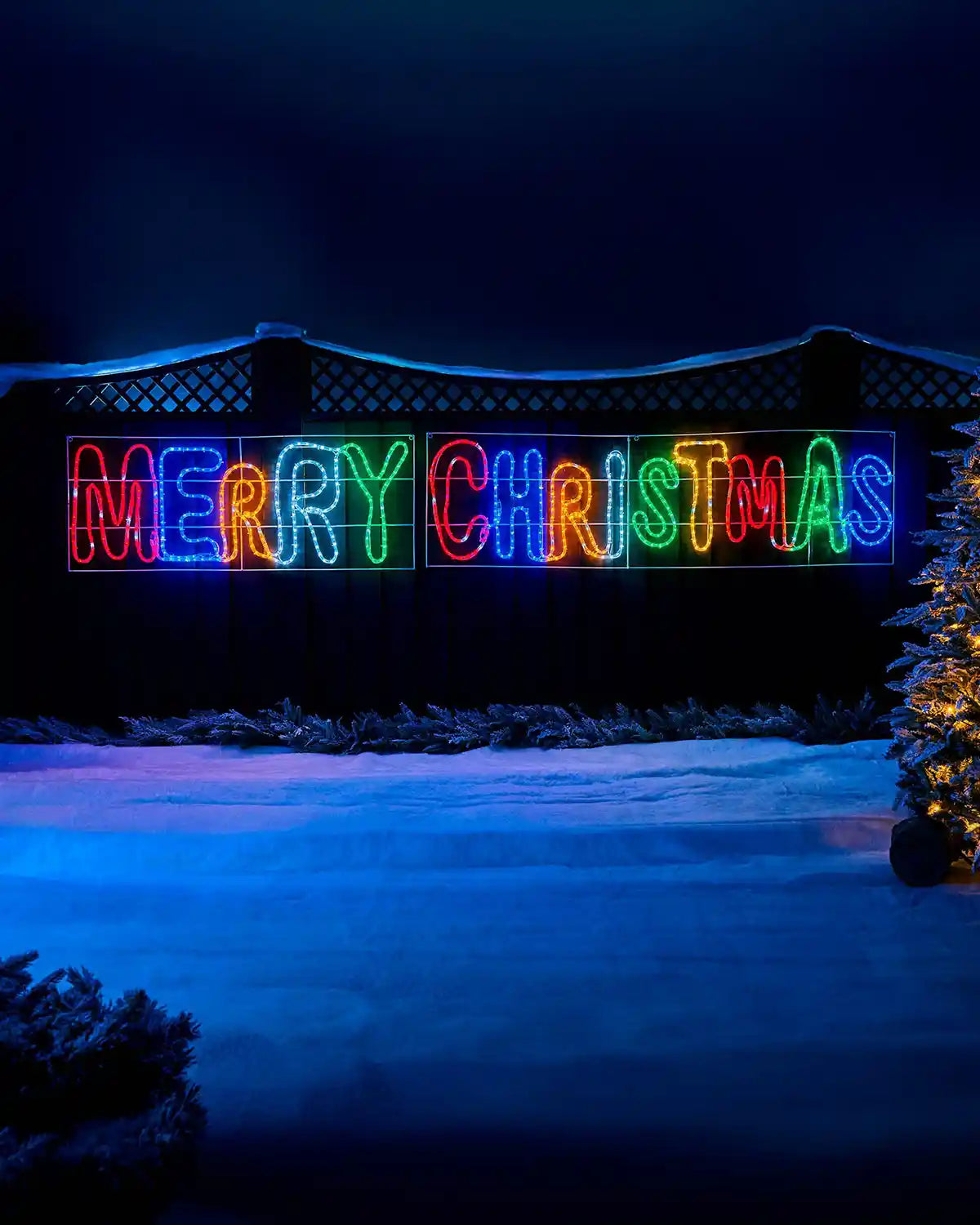Pre-Lit Merry Christmas, Multi-Coloured, Silhouette, 292 cm on a garden fence with snow on the ground at night time