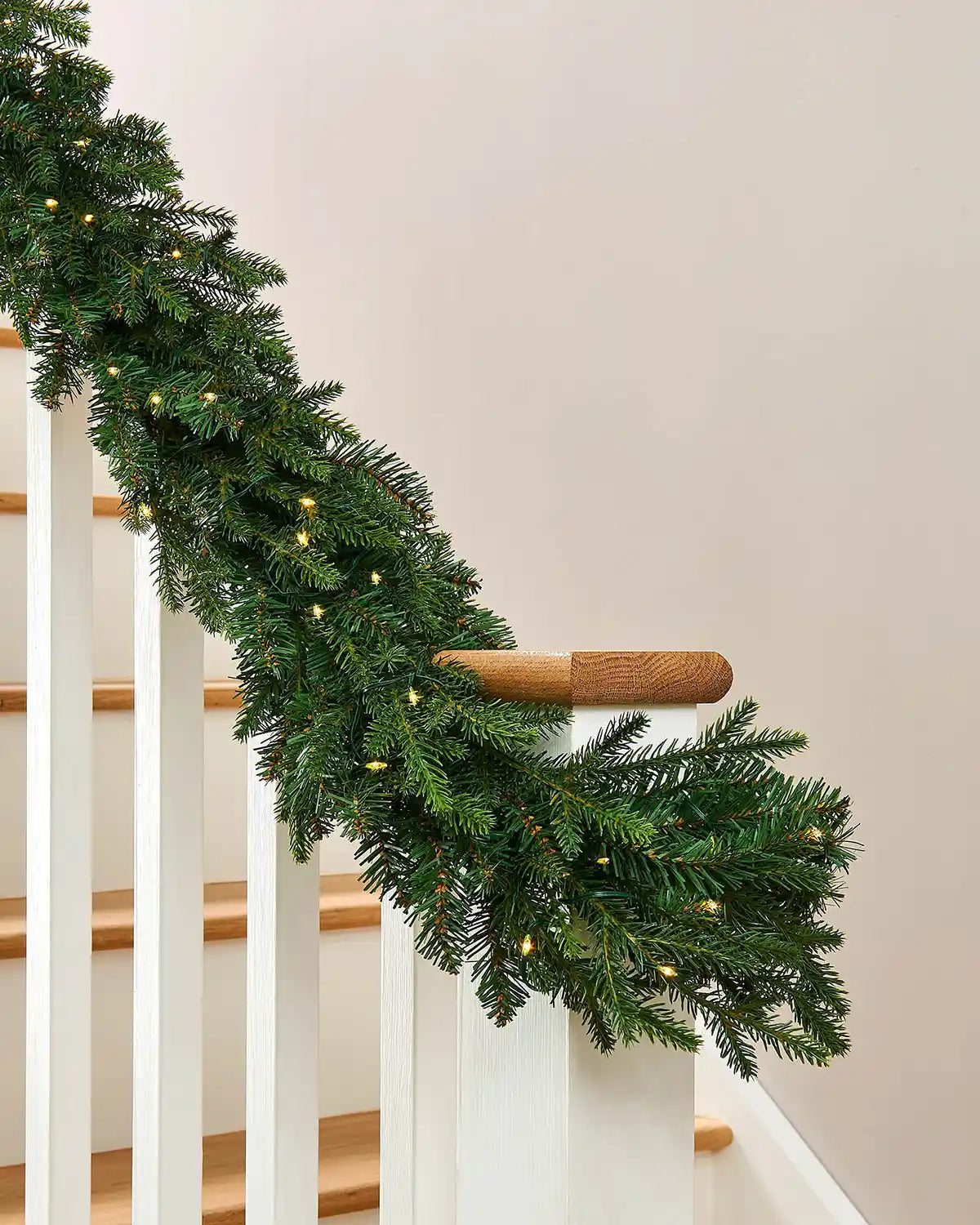 Decorative Christmas garland with lights on a wooden staircase banister 