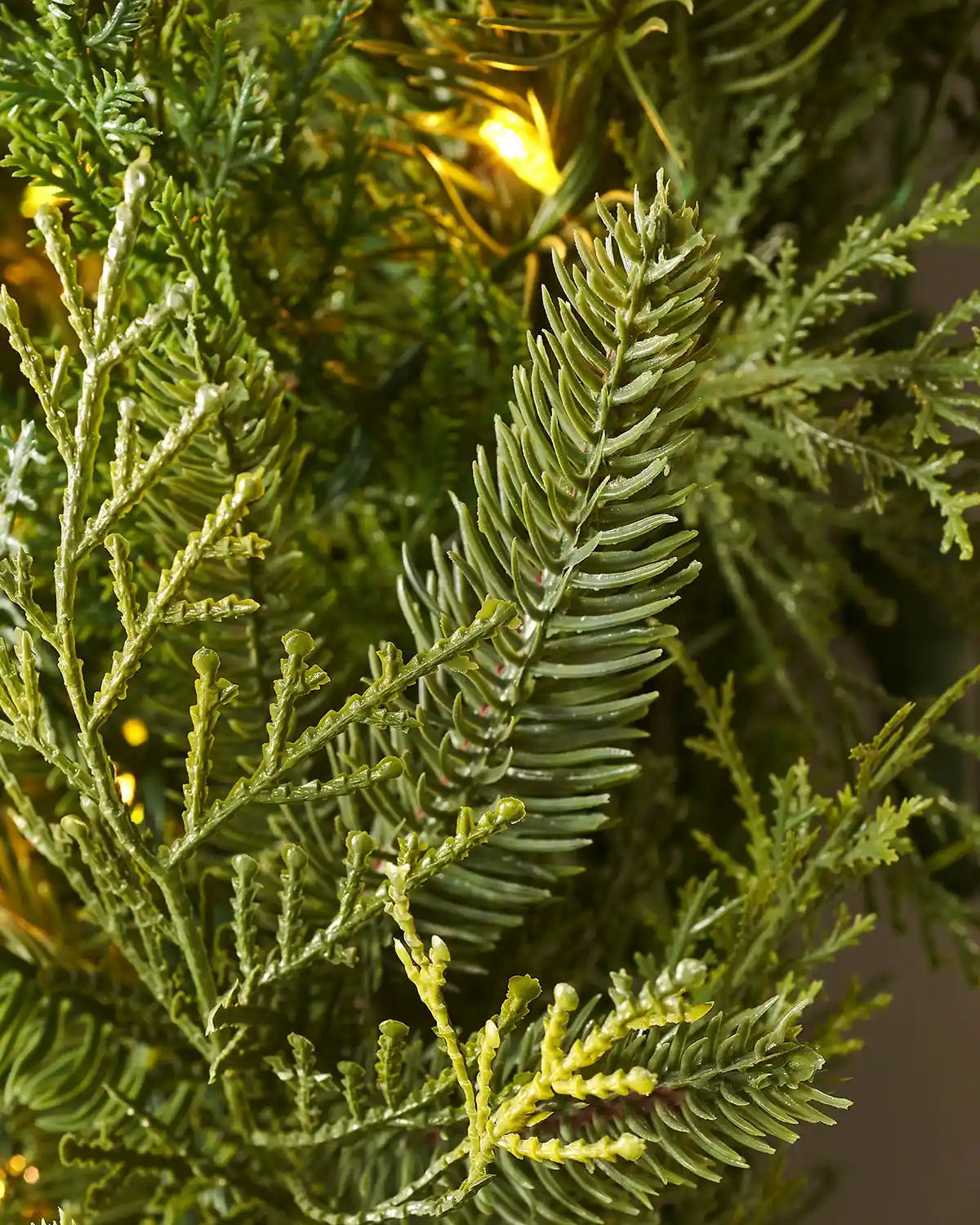 Close up of the PE tips and single lit Warm White bulbs of a Pre-Lit Natural Fir Majestic Wreath, 1.5 m