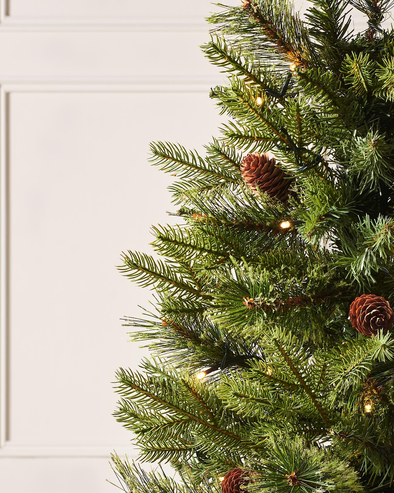 A 3.5-foot pre-lit natural pine potted Christmas tree with warm white LED lights and decorative berries, placed in a black potter