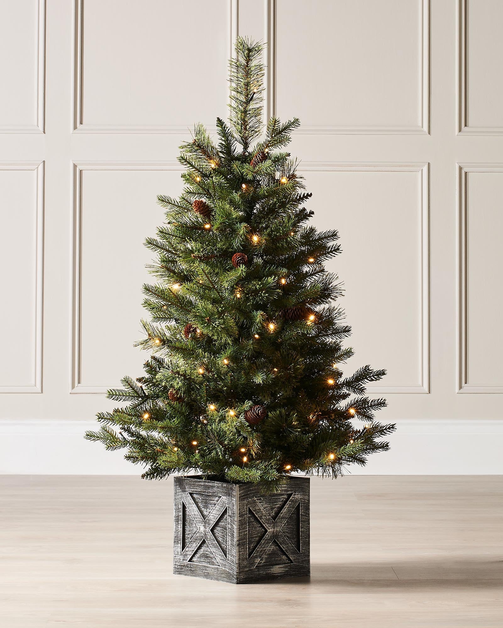 A 3.5-foot pre-lit natural pine potted Christmas tree with warm white LED lights and decorative berries, placed in a black potter