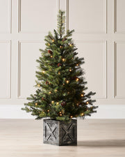A 3.5-foot pre-lit natural pine potted Christmas tree with warm white LED lights and decorative berries, placed in a black potter