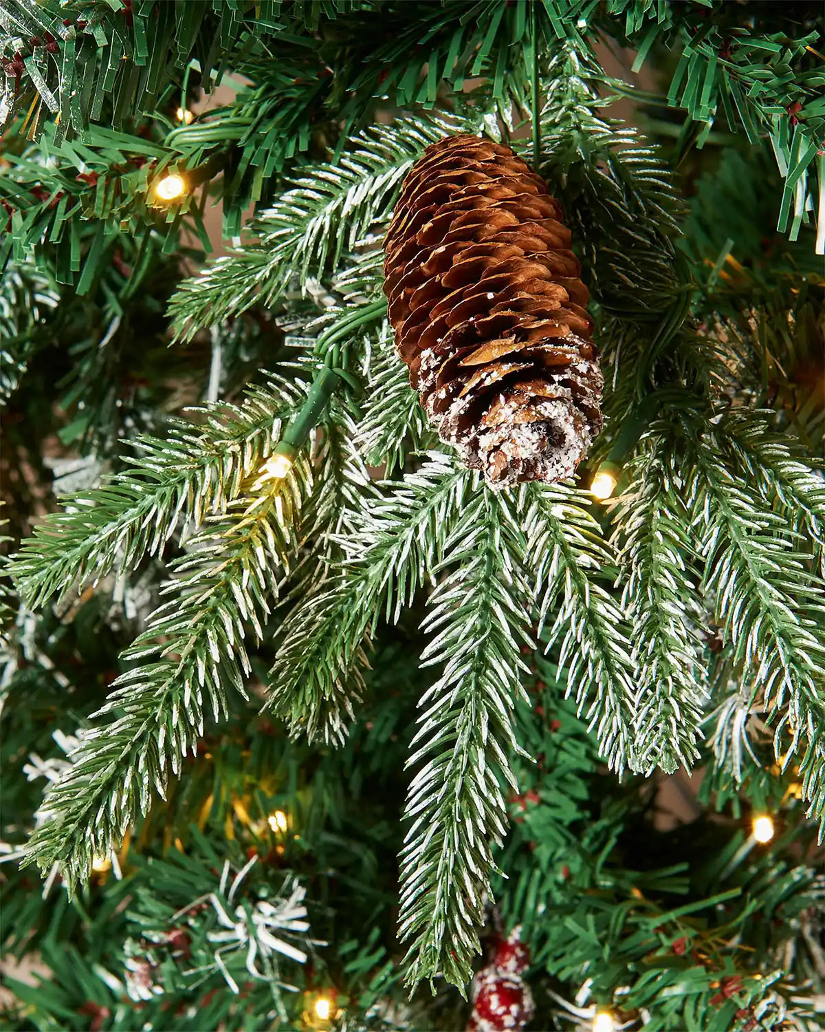 Close up of pine cone and Lights on Pre-Lit Snow Flocked Norwegian Spruce Christmas Tree with Pine cones and Red berries, 6 ft
