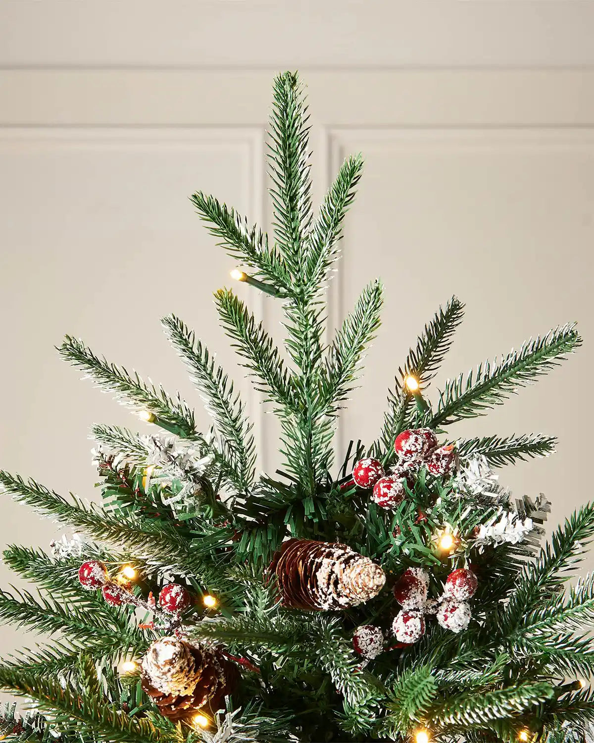 Close up of the top of the tree of Pre-Lit Snow Flocked Norwegian Spruce Christmas Tree with Pine cones and Red berries, 6 ft