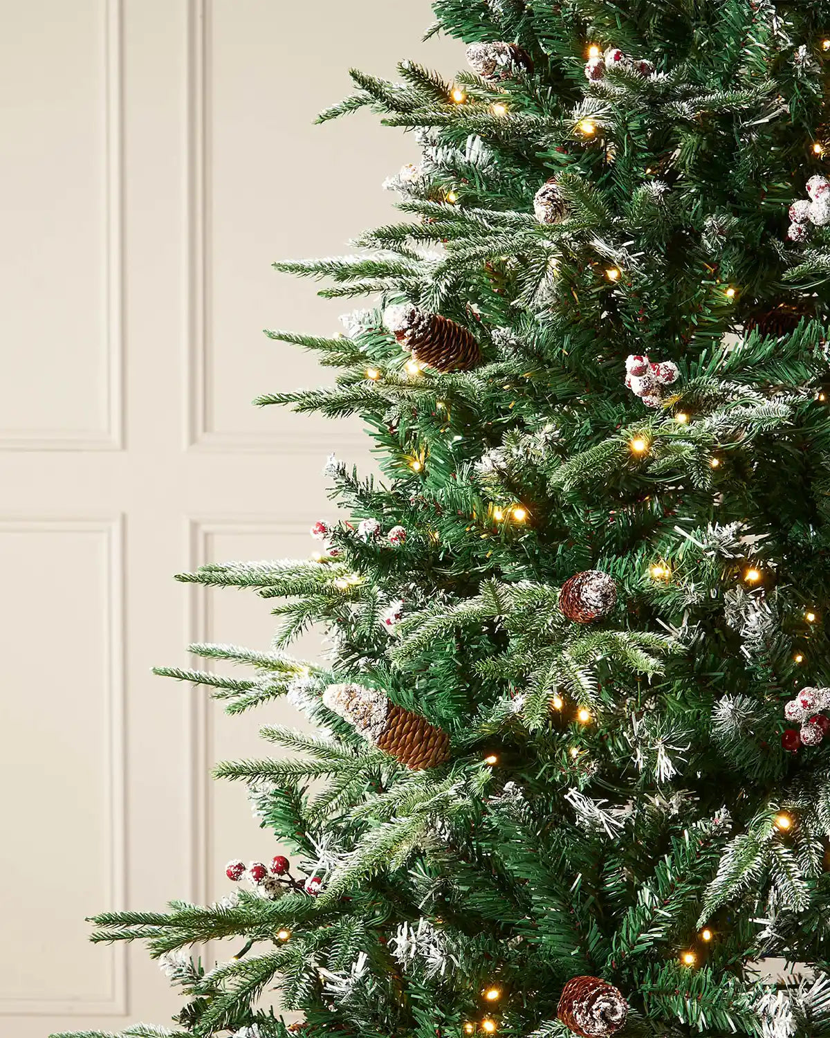 Close up of Red berries and Pinecones on Pre-Lit Snow Flocked Norwegian Spruce Christmas Tree with Pine cones and Red berries, 7 ft on a panel textured background 
