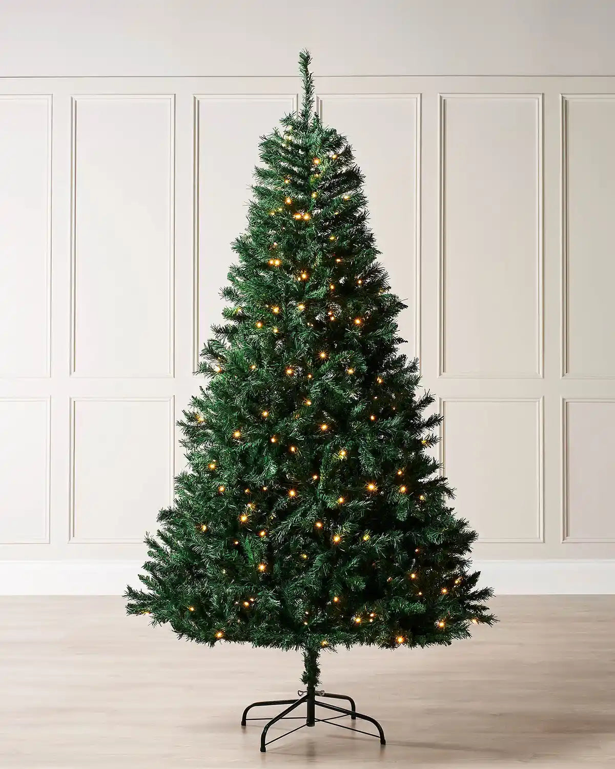 Pre-lit 7ft Christmas tree white warm white lights against a cream panel wall
