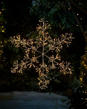 Pre Lit hanging warm white snowflake star against a winter garden setting